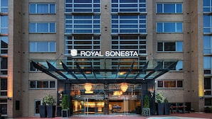 A hotel entrance with a glass canopy, multiple floors, and a sign reading 'ROYAL SONESTA'.