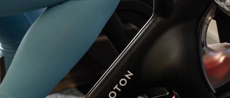 Close-up van een Peloton hometrainer met een rode versnellingsknop en een waterfleshouder.