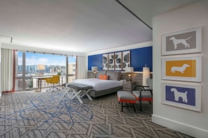 A modern hotel room with a large bed, a desk, and a view of the city.