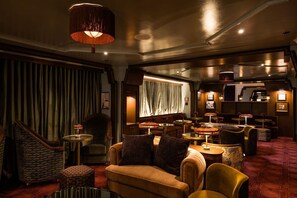 A dimly lit lounge area with a sofa, armchairs, and a bar area with stools. - The Royal Sonesta Washington DC Dupont Circle (Washington)