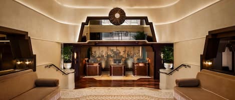 Eine geräumige Lobby mit einer imposanten Treppe, einem Empfangsbereich und einem Chandelier.