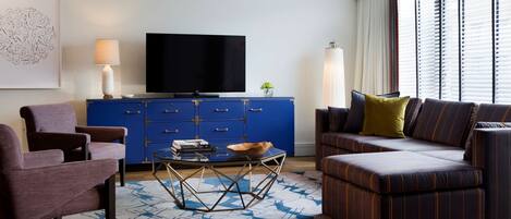 Una sala de estar moderna con un mueble azul, un televisor de pantalla plana, un sofá, una mesa de centro y una alfombra estampada.