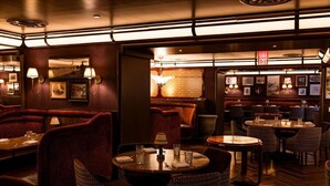 A restaurant with booths and tables, warm lighting, and framed pictures on the walls.