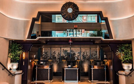A lobby with a large chandelier, a clock, and a reception desk.