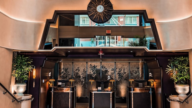 A lobby with a large chandelier, a clock, and a reception desk.