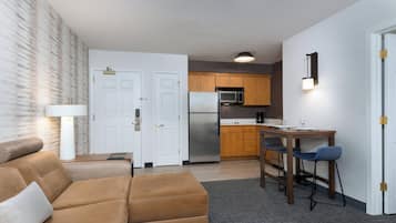 Un espacio habitable compacto con kitchenette, un sofá y una zona de comedor con taburetes de bar.
