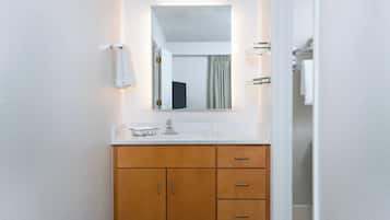 A bathroom with a white sink, wooden cabinet, and a mirror above it.