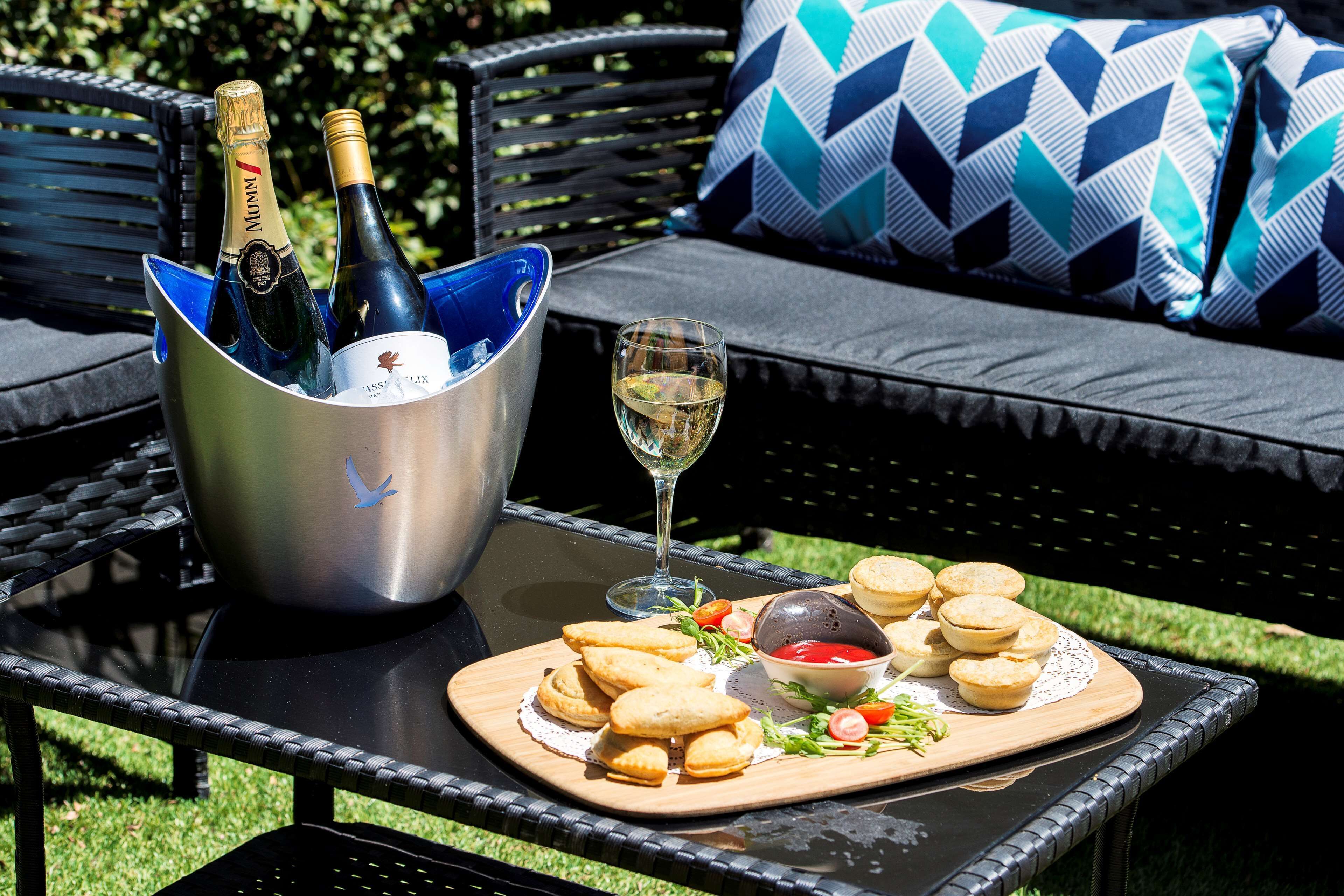 A table with a bottle of champagne, a glass of wine, and a plate of pastries.