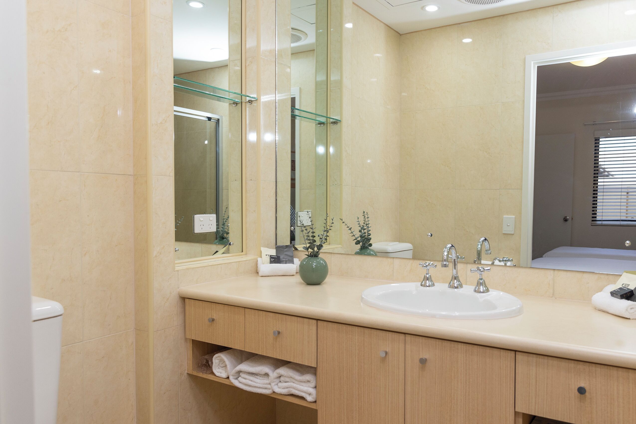 Une salle de bain moderne avec un grand miroir, un lavabo et une douche à l’italienne.