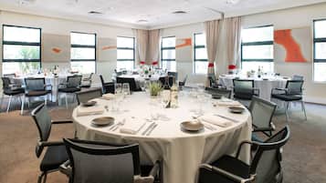 A conference room with round tables, chairs, and dining setup.