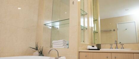 A modern bathroom with a large bathtub, a vanity with a mirror, and a glass shower enclosure.