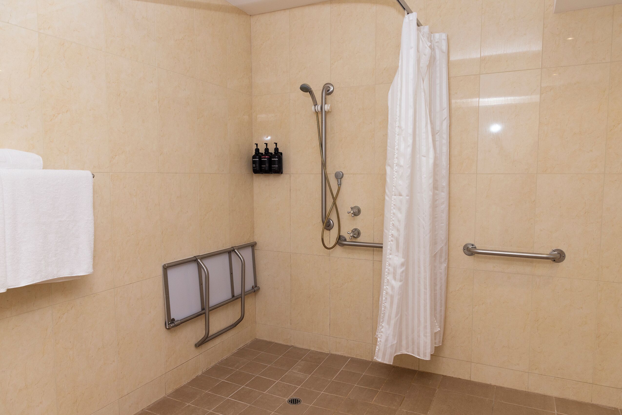 A shower area with a grab bar, a showerhead, and a curtain.