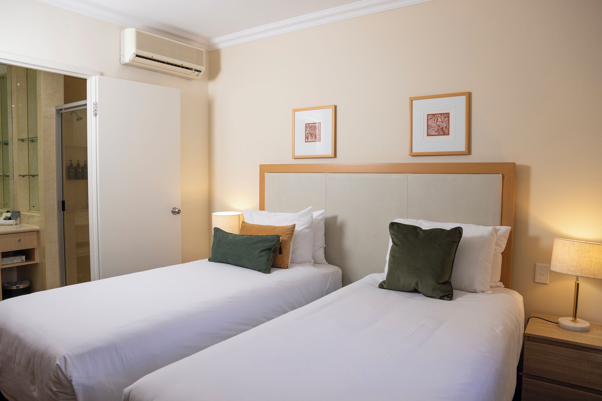 A hotel room with two beds, a bathroom, and a shower.
