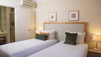 A hotel room with two beds, a bathroom, and a shower.
