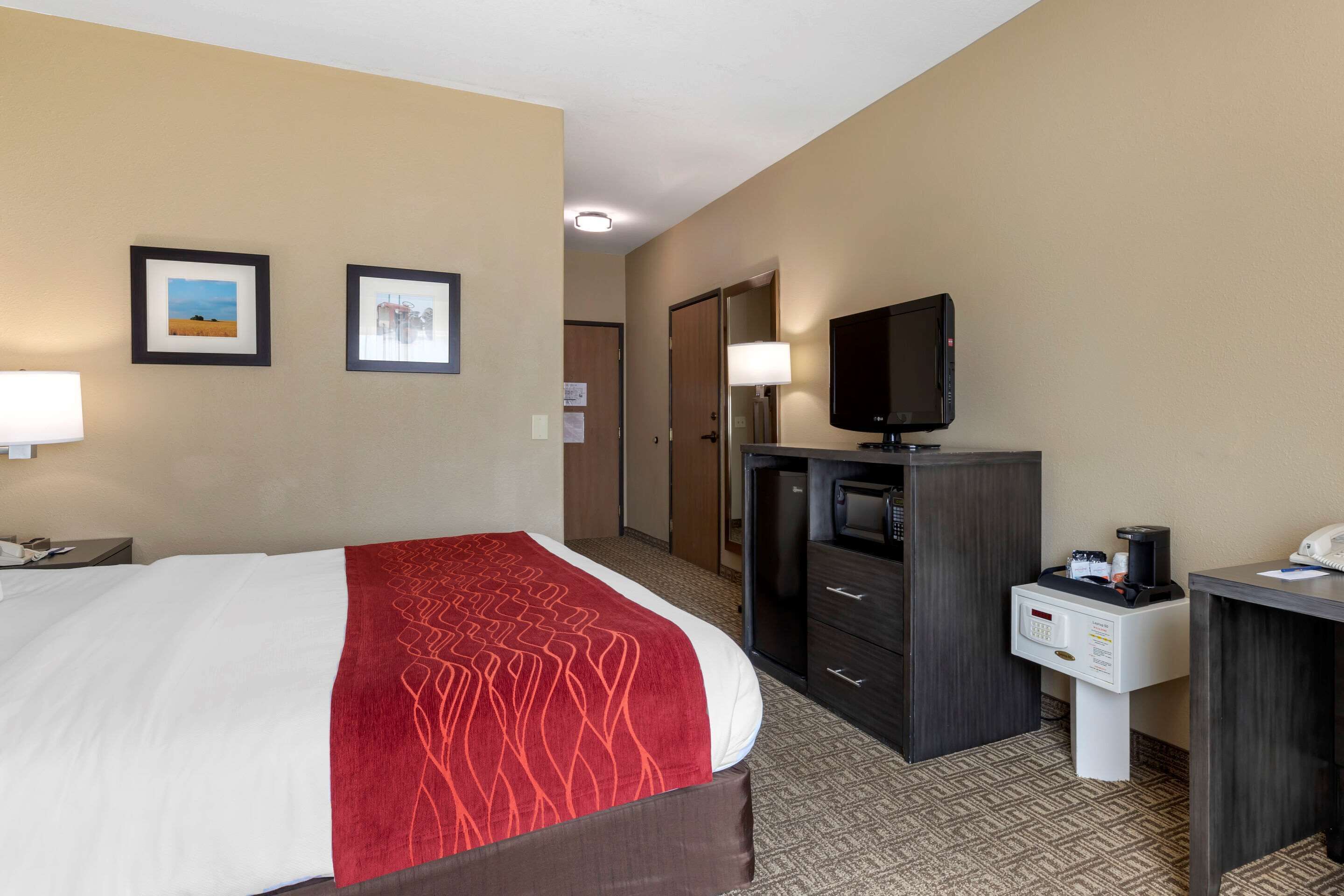 Una camera d'albergo con un letto, una scrivania, una televisione e un minibar.