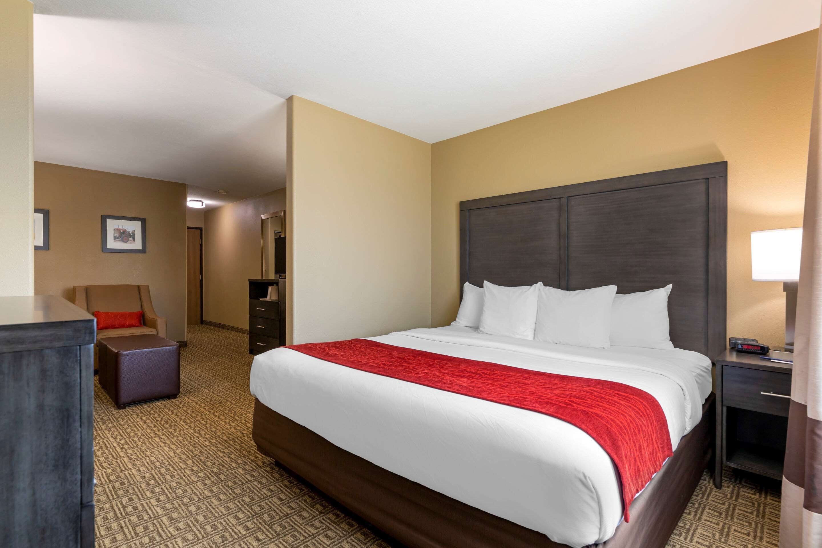 A hotel room with a large bed, a nightstand, a chair, and a desk.