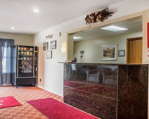 A reception area with a marble counter, a vending machine, framed pictures on the wall, and a red carpet. - Econo Lodge Cuba I-86 (Cuba)