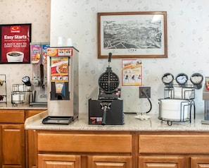 A coffee station with a coffee machine, waffle maker, and waffle iron. There is a framed map of Cuba on the wall. - Econo Lodge Cuba I-86 (Cuba)