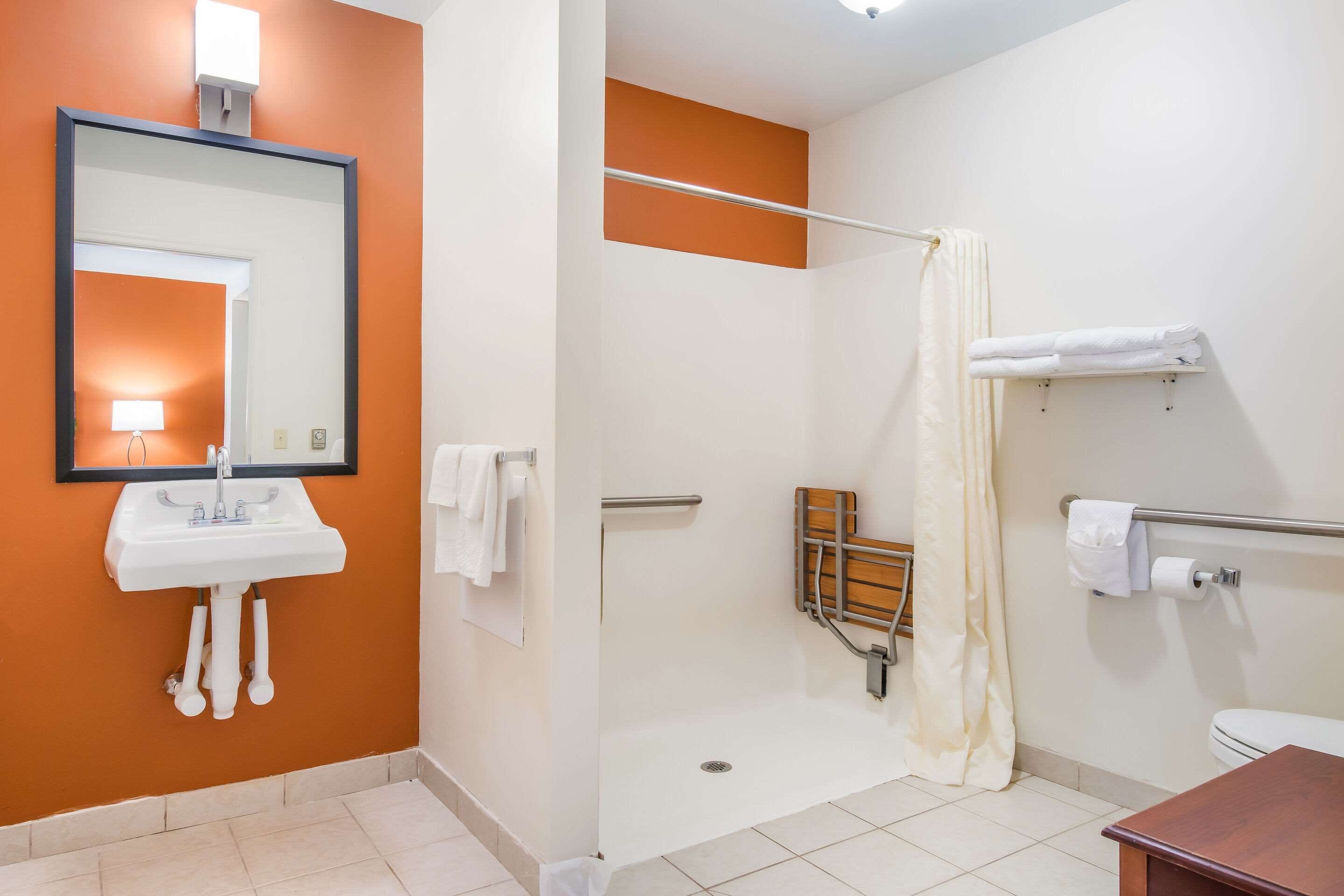 Une salle de bain équipée d’un lavabo, d’un miroir, d’une douche, de toilettes et d’un porte-serviettes.