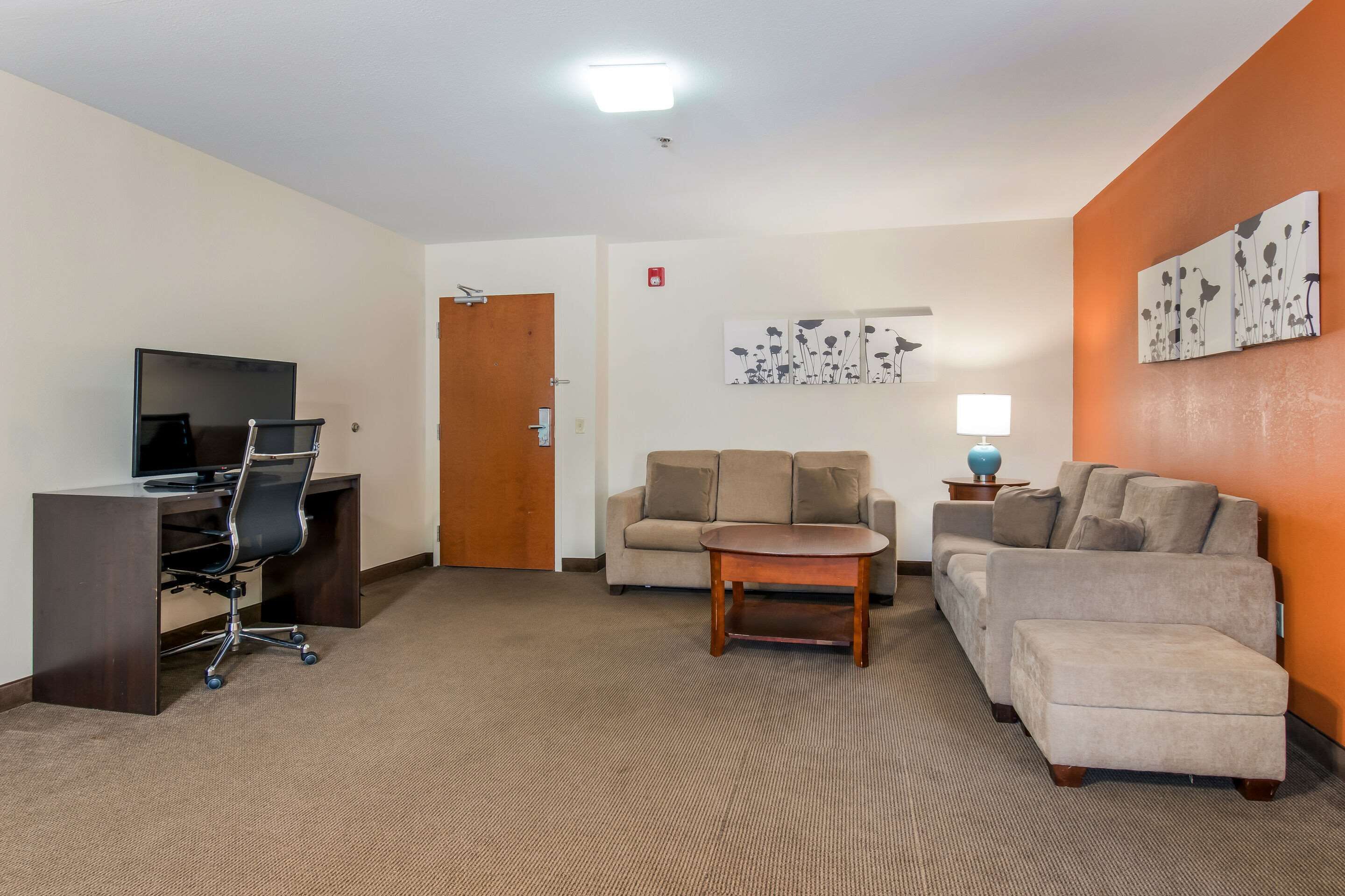 A furnished living room with a desk, two sofas, a coffee table, and artwork on the walls.