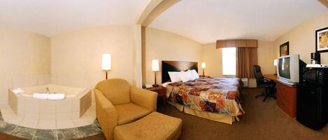 A hotel room with a bed, a chair, a desk with a television and a microwave, and a bathtub.