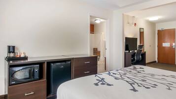 A hotel room with a bed, a desk with a computer, a microwave, and a coffee maker.