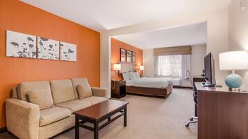 A hotel room with a sofa, a bed, a desk, and a television.