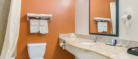 Un baño con pared naranja, inodoro blanco y un lavabo con espejo.
