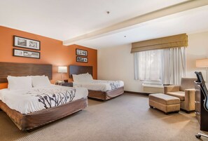 A hotel room with two beds, a desk, a chair, and a dresser.
