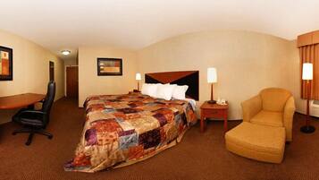 A hotel room with a large bed, a desk, a chair, and a nightstand with lamps.
