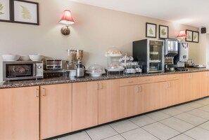A kitchen with a microwave, toaster, coffee maker, and a refrigerator.