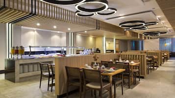 Restaurante moderno com área de buffet, mobiliário de madeira e luminárias contemporâneas.