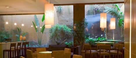 Un ristorante con vista su una cascata, piante da interno e diverse opzioni di posti a sedere.