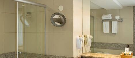 A modern bathroom with a glass shower enclosure, a granite countertop sink, and a large mirror.