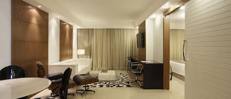 Una habitación de hotel moderna con una cama grande, un escritorio, una silla, una mesa y un baño.