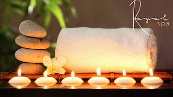 Una pila de piedras, una toalla blanca y velas encendidas sobre una superficie de madera.
