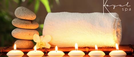 Una pila de piedras, una toalla blanca y velas encendidas sobre una superficie de madera.