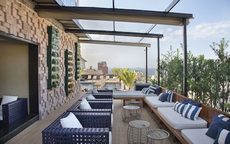 A rooftop terrace with seating areas, a pool, and a view of the cityscape.
