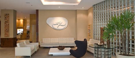 A modern lobby with a sofa, armchairs, a coffee table, and a large wall art piece.