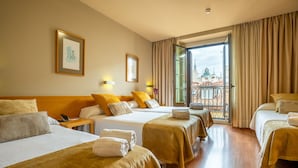 A hotel room with three beds, a balcony, and a view of the cityscape. - Hotel Victoria 4 (Madrid)