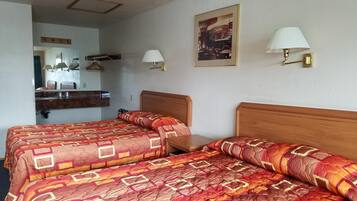 Ett hotellrum med två sängar, en sänggavel i trä, en spegel, ett litet bord och två vägglampor.