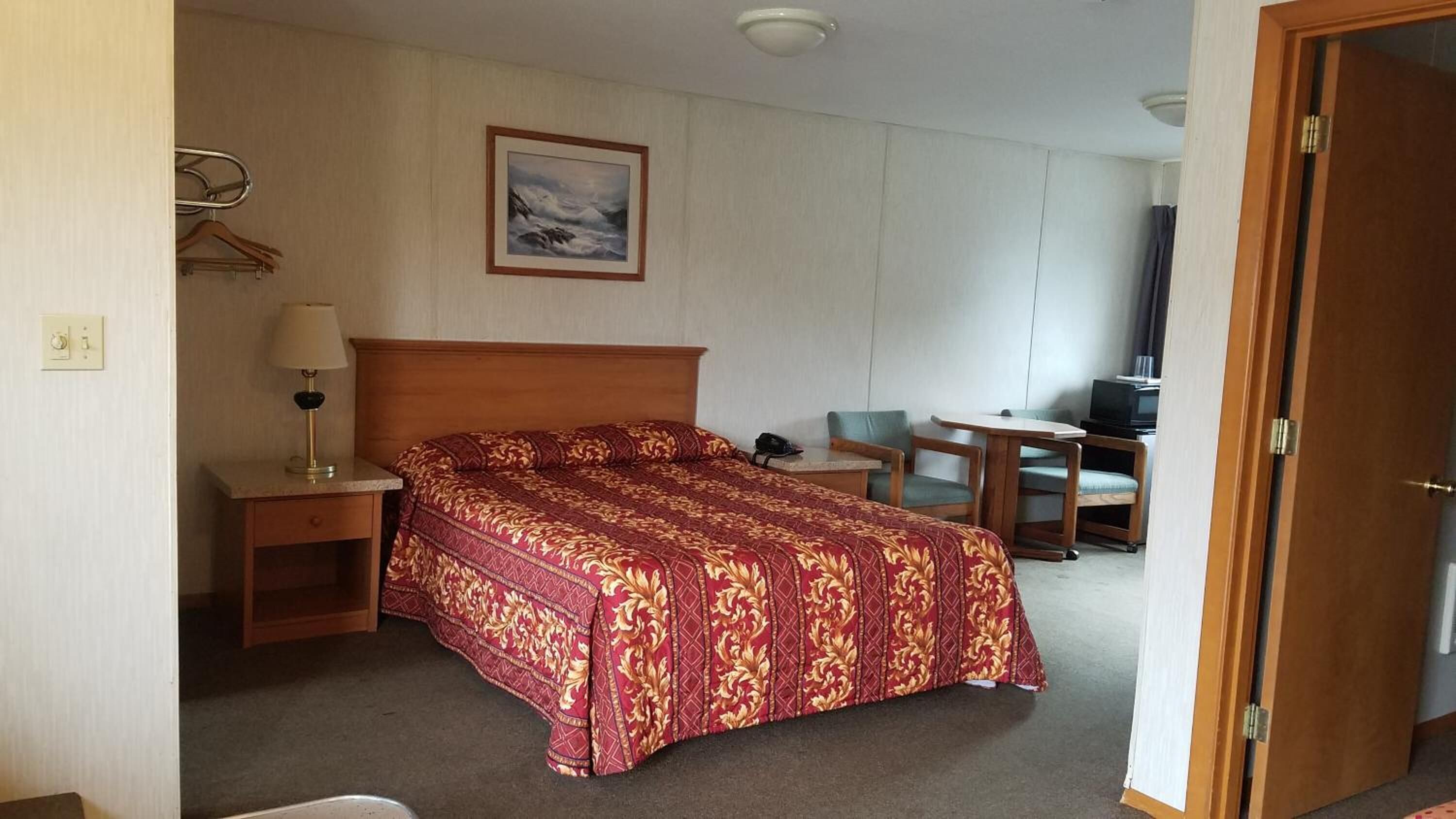 Een hotelkamer met een groot bed, een bureau, een stoel, een televisie en een schilderij aan de muur.