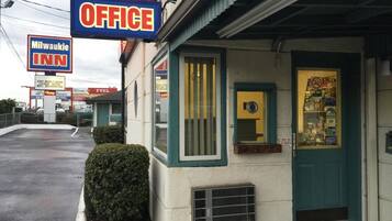 A small office building with a sign reading "OFFICE" and a window displaying various items.