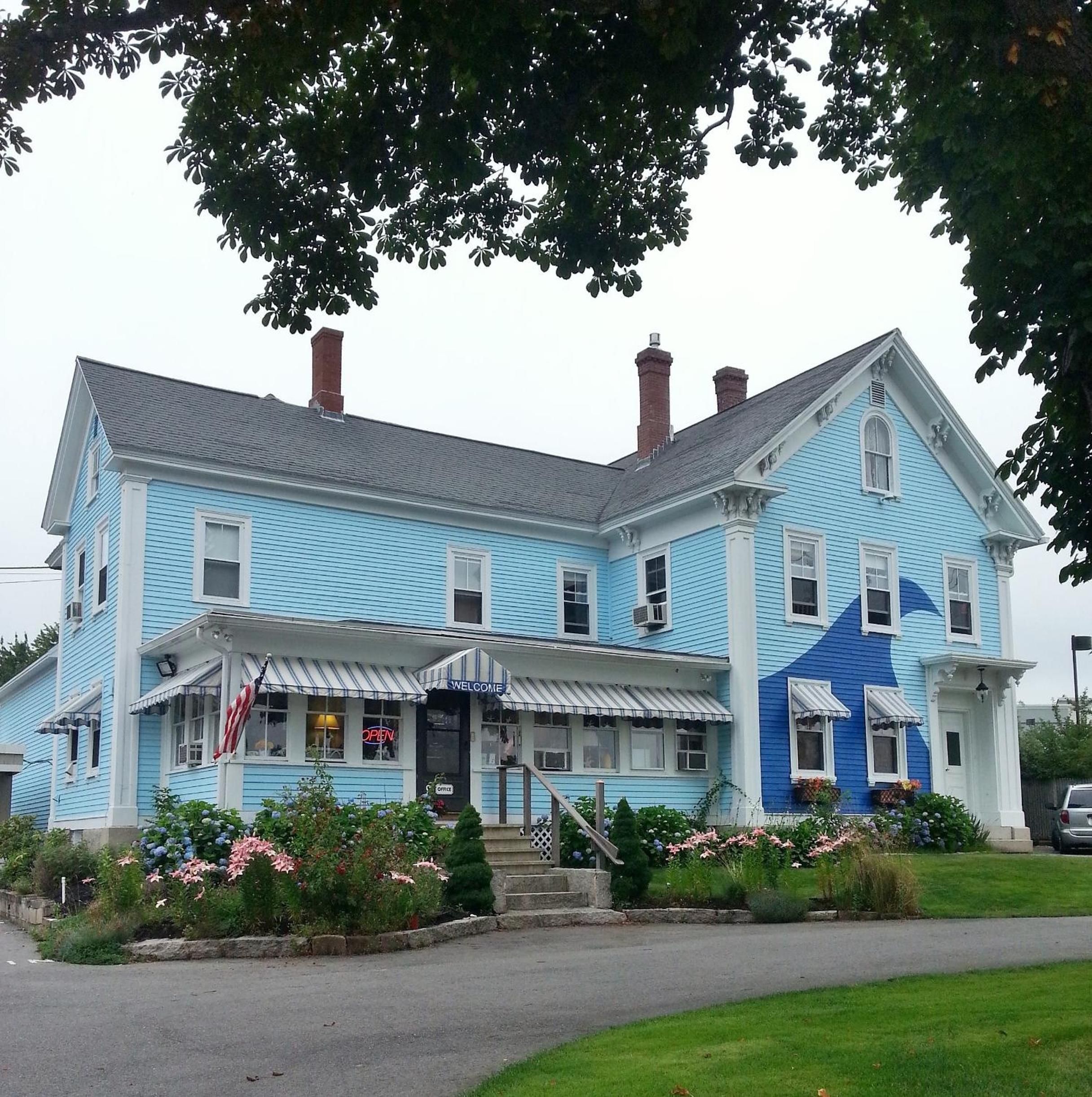 A large, two-story building with a blue exterior, a welcoming entrance with a porch, and a staircase leading to the front door.