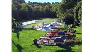 Un área de picnic con mesas, sombrillas y una parrilla.