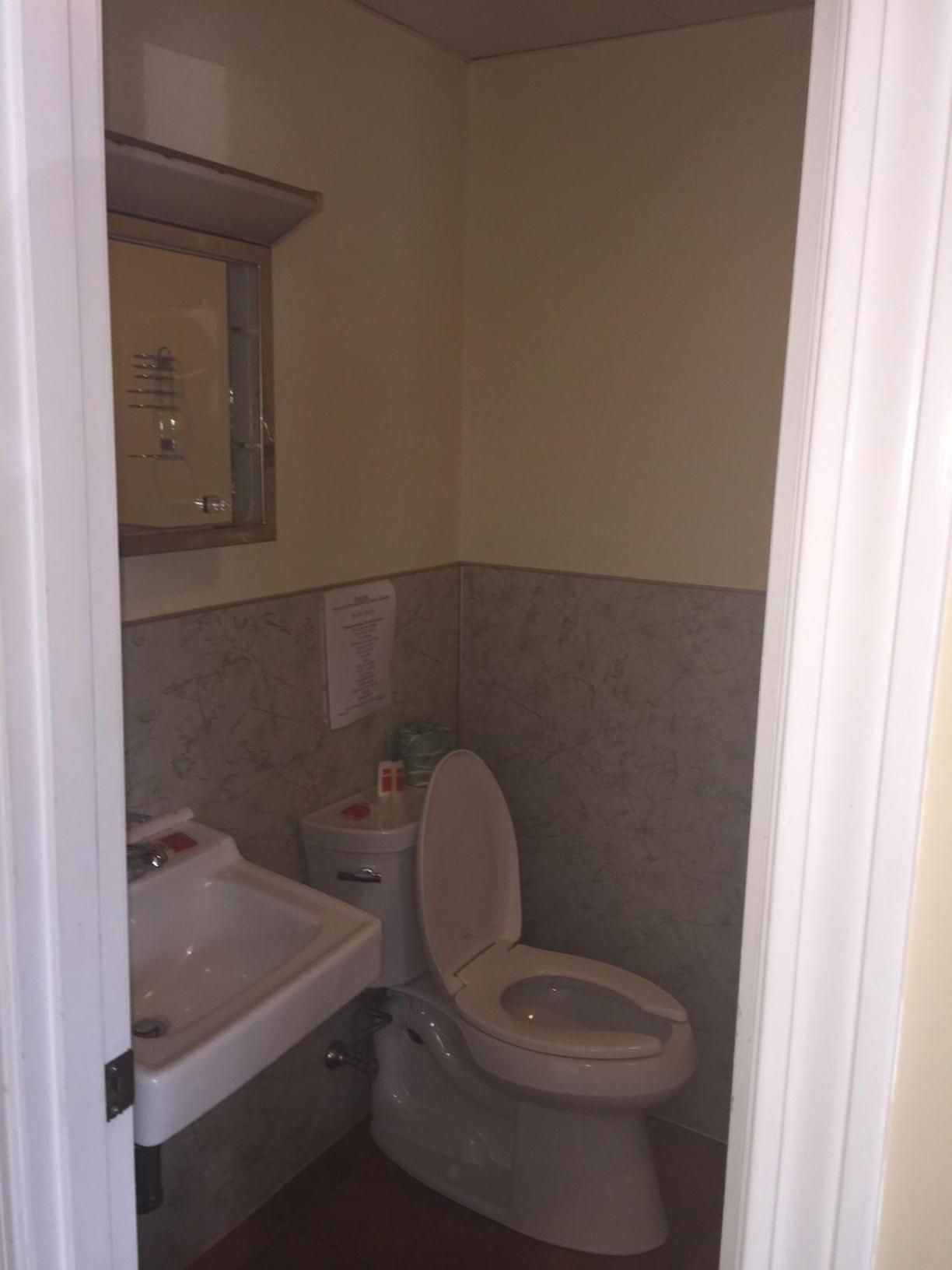Ein kleines Badezimmer mit Toilette, Waschbecken und Spiegel.
