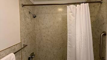 A bathroom with a bathtub, a shower curtain, a towel rack, and a ceiling light.