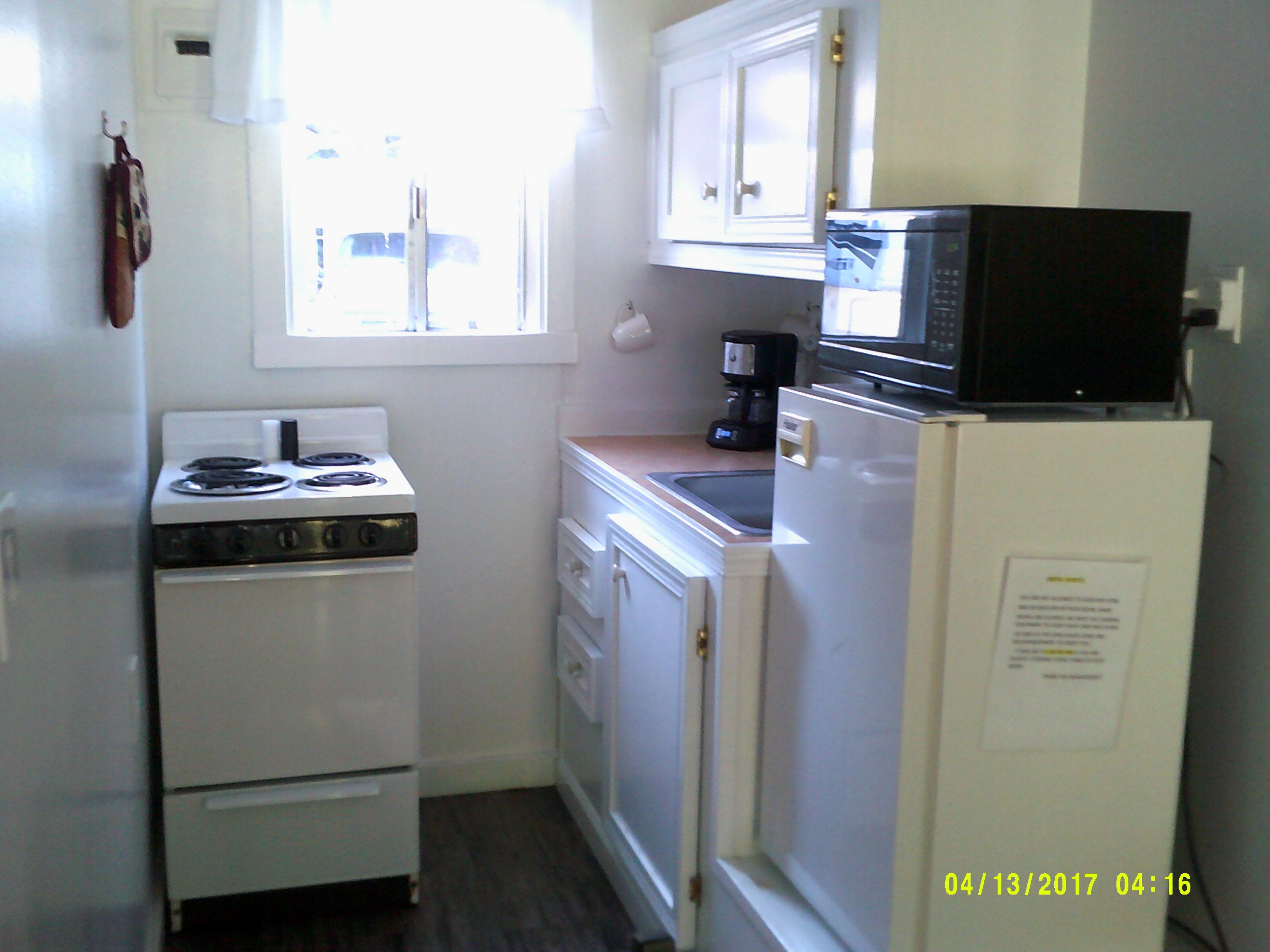 Una cocina compacta con estufa, microondas y refrigerador.