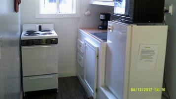 Una cocina compacta con estufa, microondas y refrigerador.