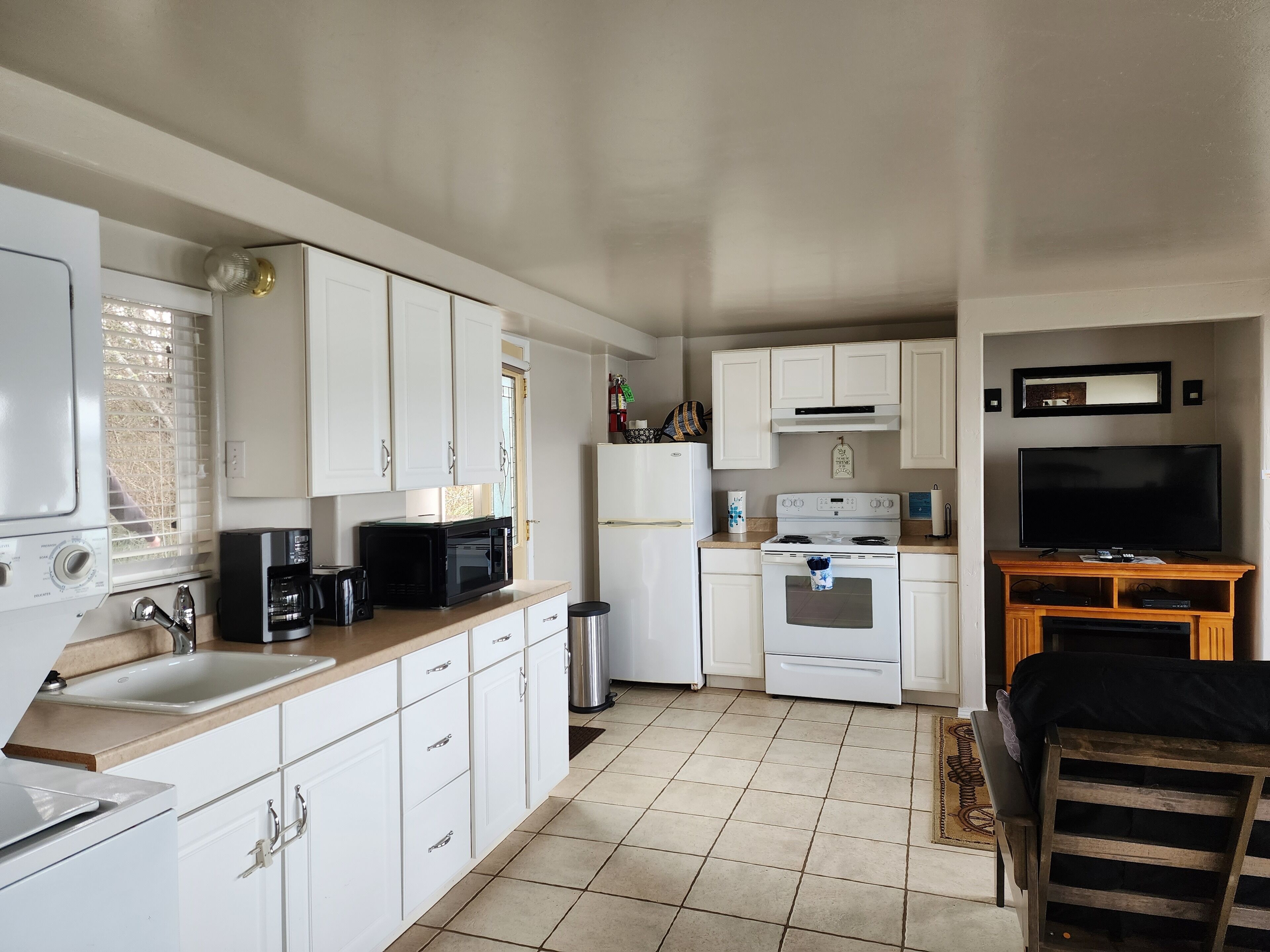 Una cocina compacta con armarios blancos, estufa, microondas y fregadero.